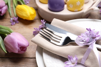Photo of Festive Easter table setting with floral decor on wooden background, closeup