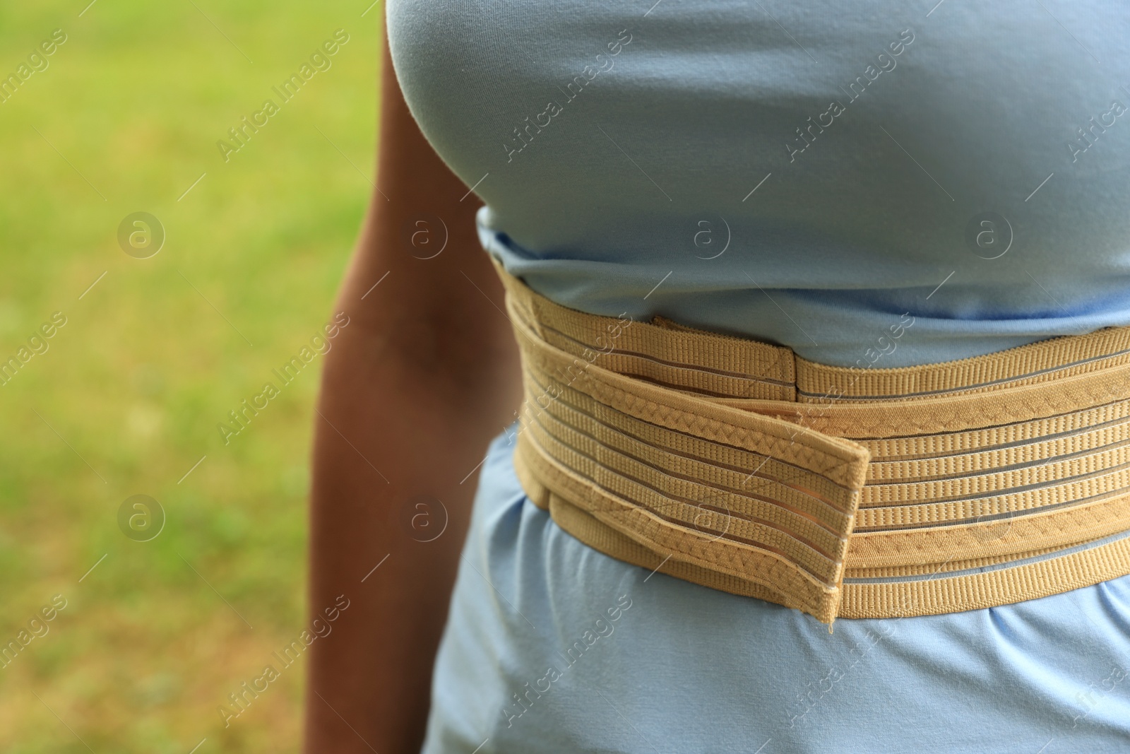 Photo of Closeup view of woman with orthopedic corset on blurred background