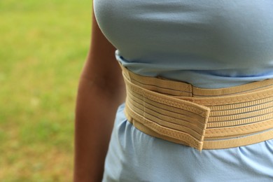 Closeup view of woman with orthopedic corset on blurred background