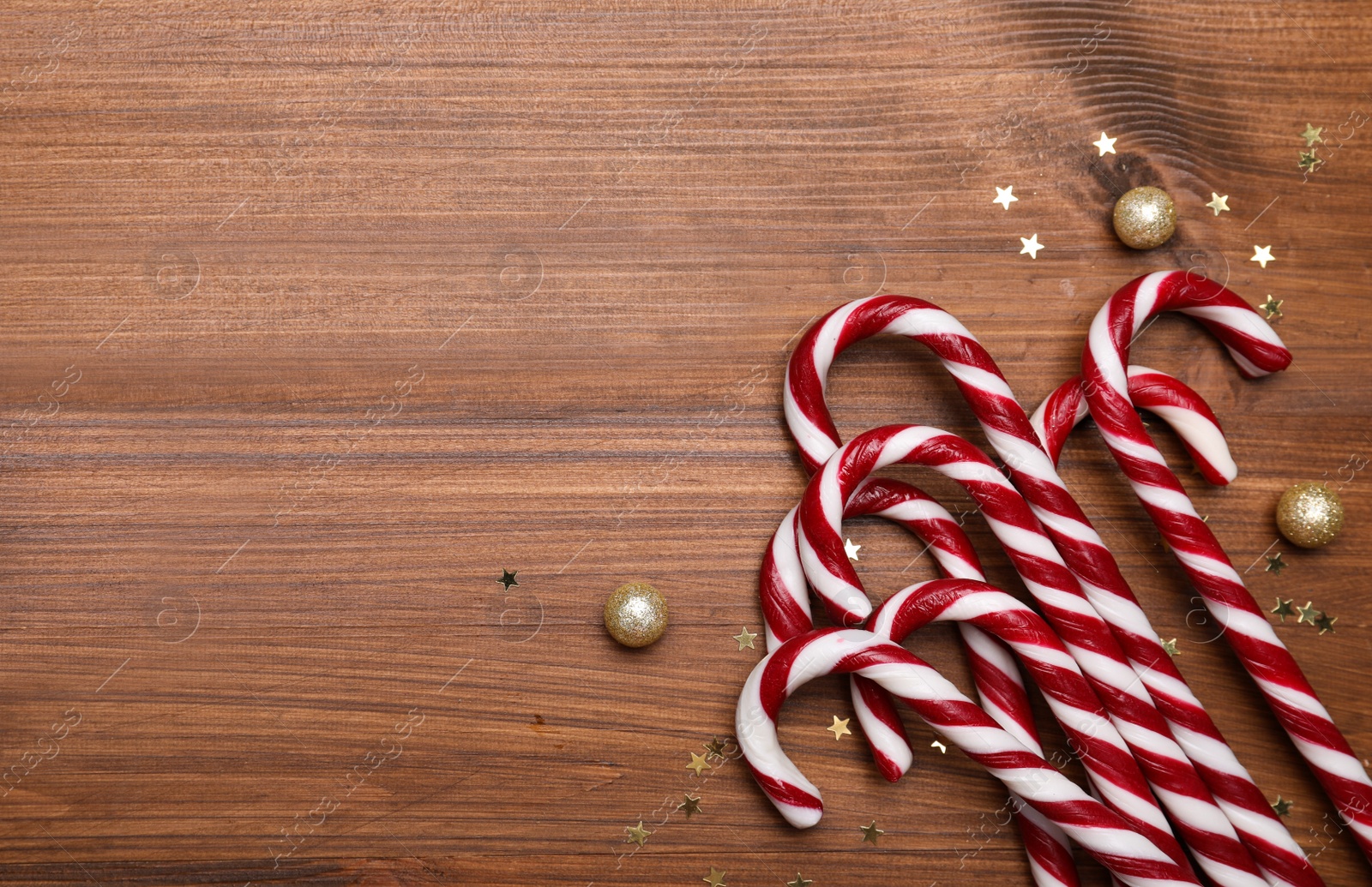 Photo of Sweet Christmas candy canes and festive decor on wooden table, flat lay. Space for text