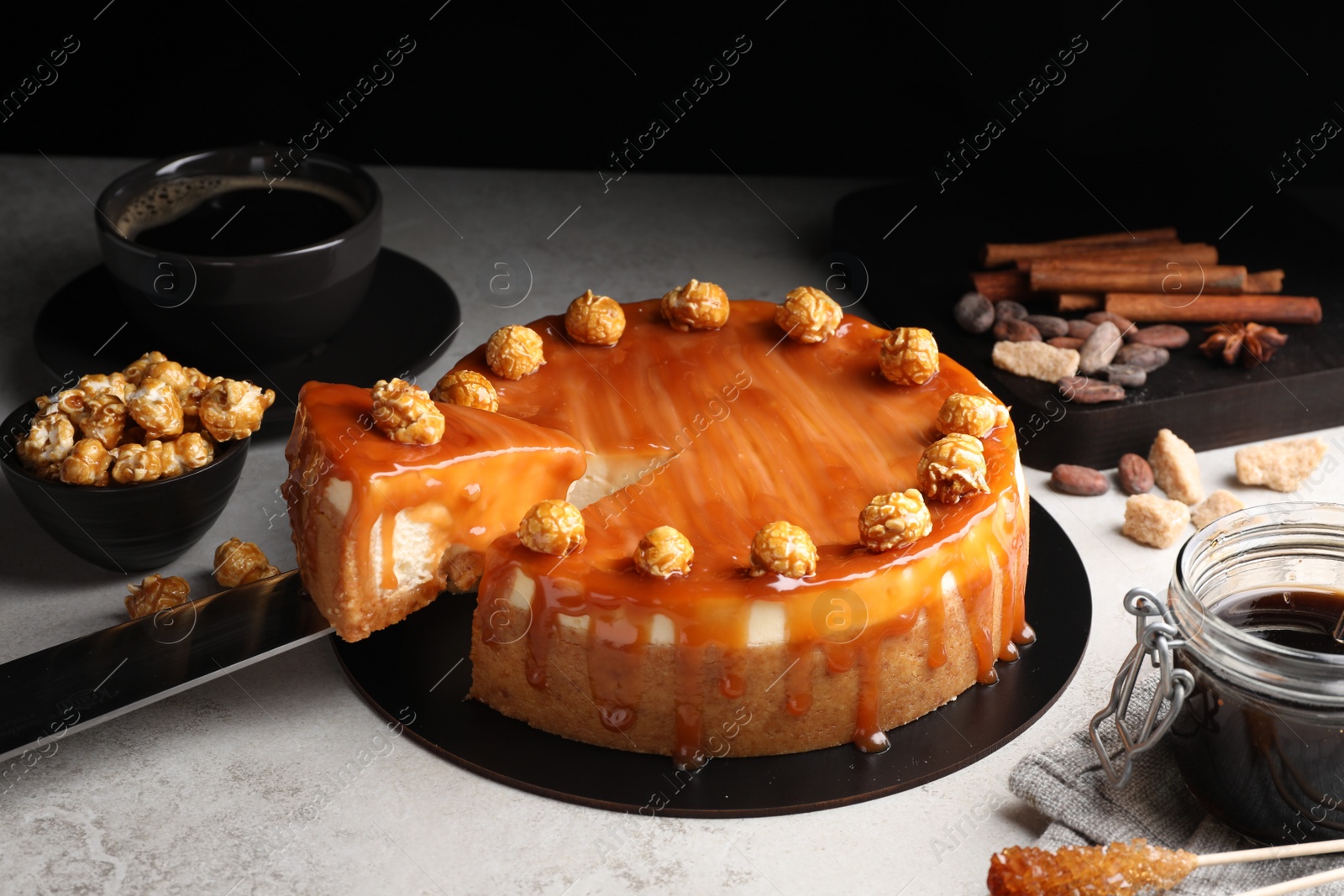 Photo of Taking piece of delicious caramel cheesecake with popcorn on light grey table