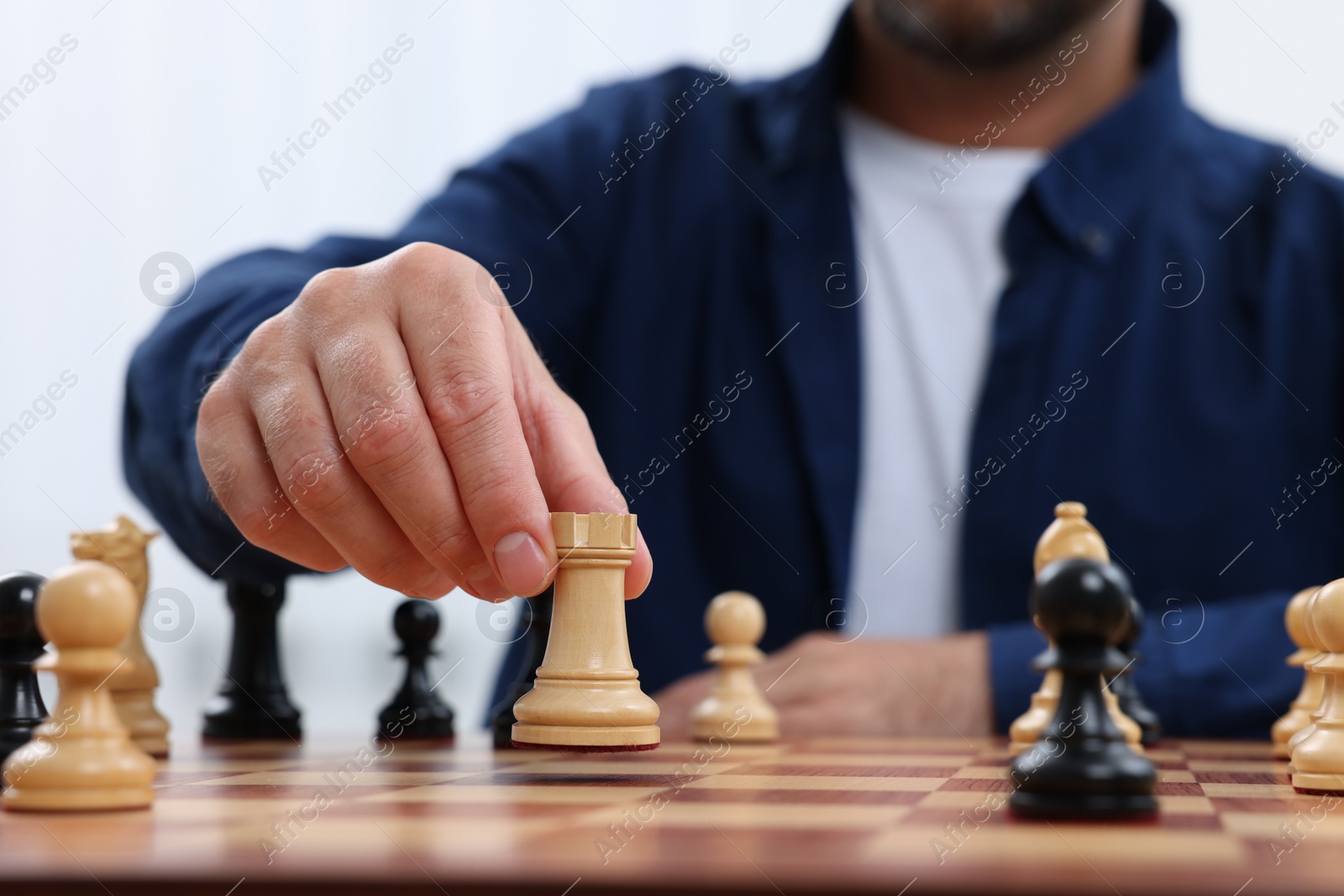 Photo of Man with rook game piece playing chess at checkerboard, closeup