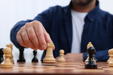 Man with rook game piece playing chess at checkerboard, closeup
