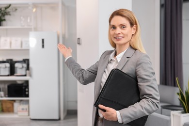 Photo of Happy real estate agent with leather portfolio indoors