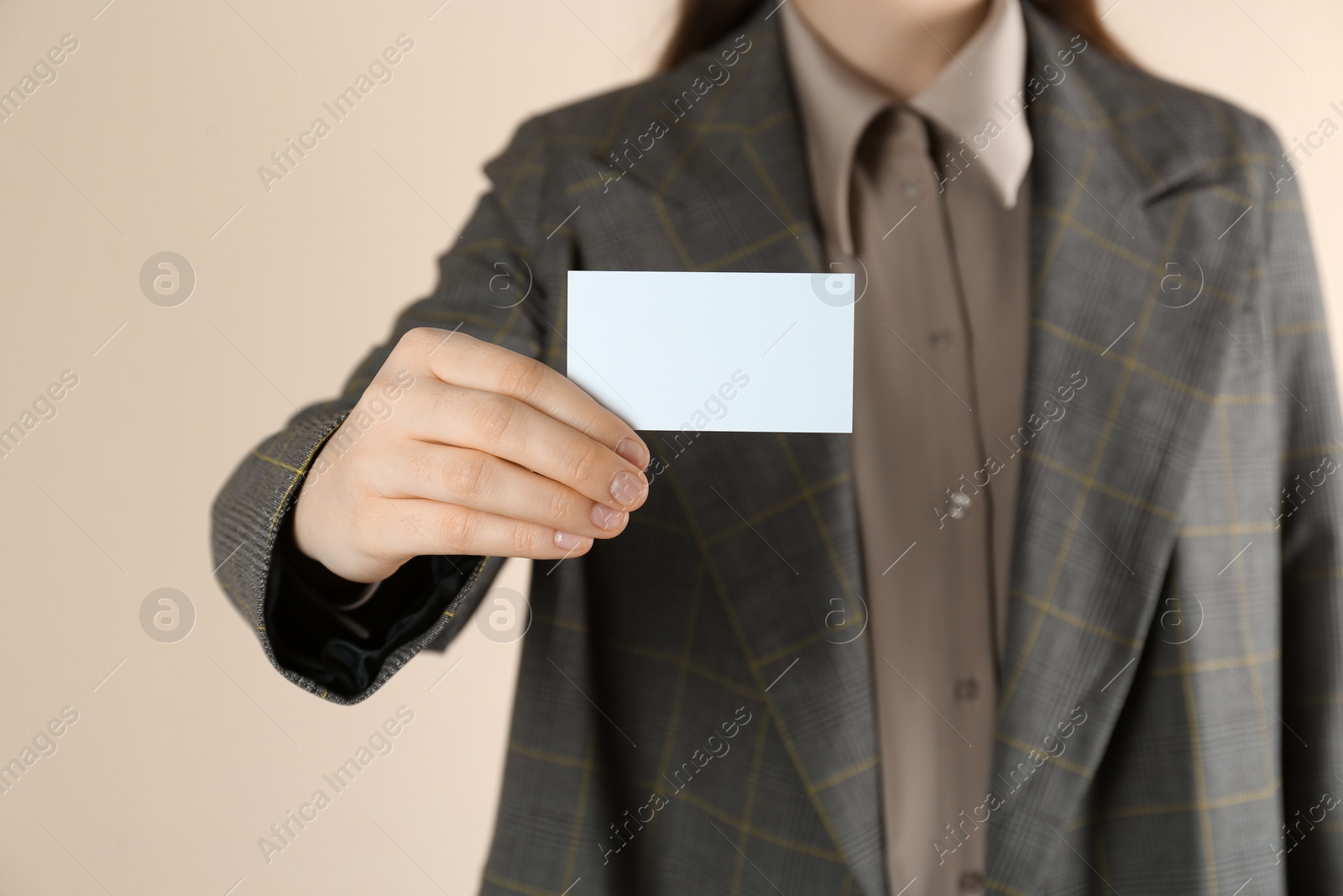 Photo of Woman holding white business card on beige background, closeup