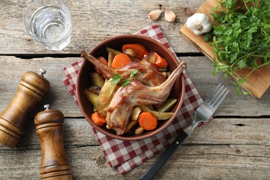 Photo of Tasty cooked rabbit with vegetables served on wooden table, flat lay