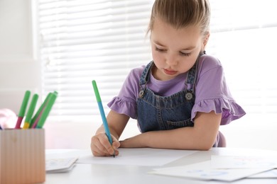 Little girl writing in classroom at English lesson