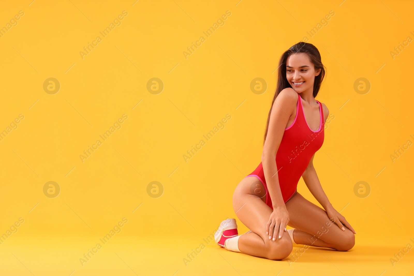 Photo of Young woman in stylish swimsuit on yellow background, space for text