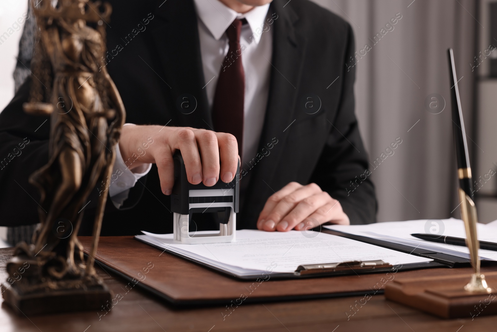 Photo of Notary stamping document at wooden table in office, closeup