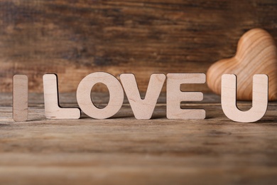 Photo of Phrase I Love U and heart on wooden table