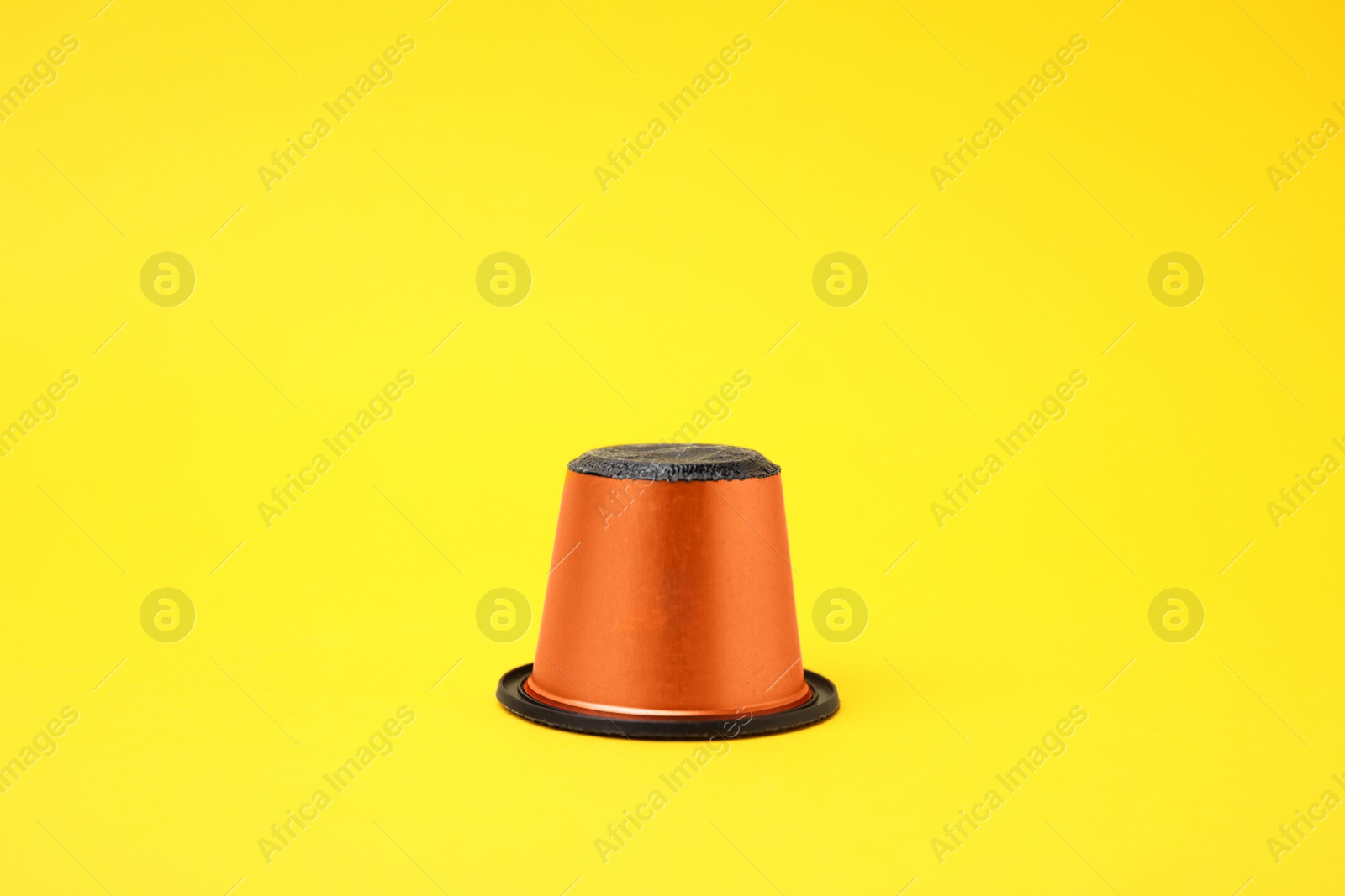 Photo of One plastic coffee capsule on yellow background