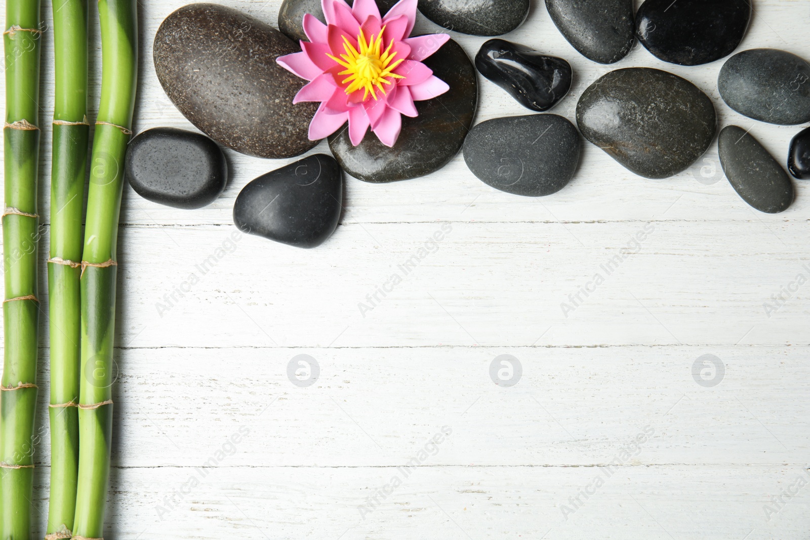 Photo of Stones, bamboo, lotus flower and space for text on white wooden background, flat lay. Zen lifestyle