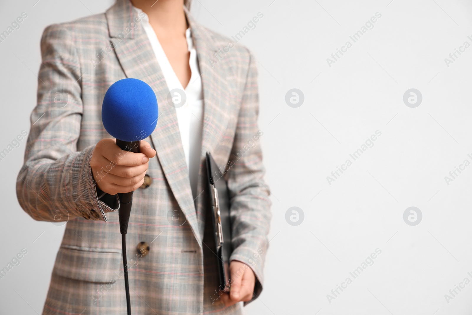 Photo of Journalist with microphone and clipboard on light background, closeup. Space for text
