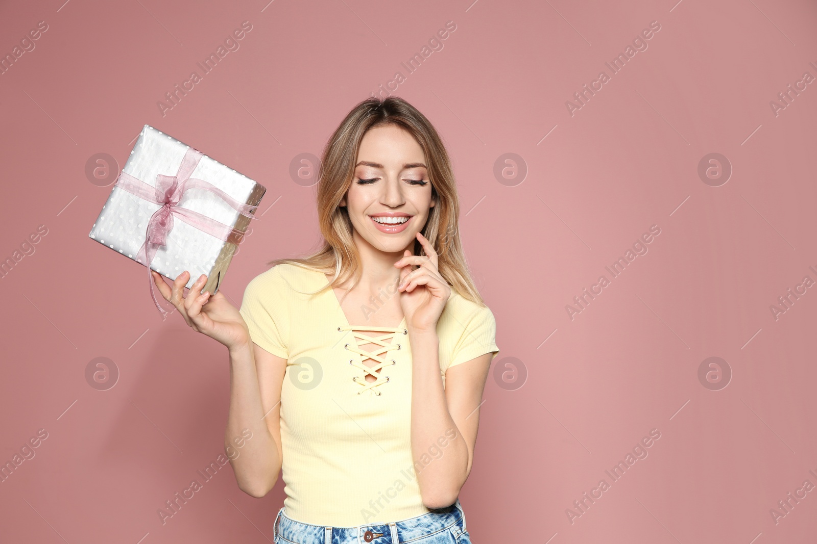 Photo of Portrait of beautiful smiling girl with gift box on pink background, space for text. International Women's Day