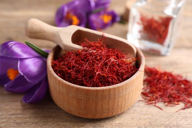 Photo of Dried saffron and crocus flowers on wooden table, closeup