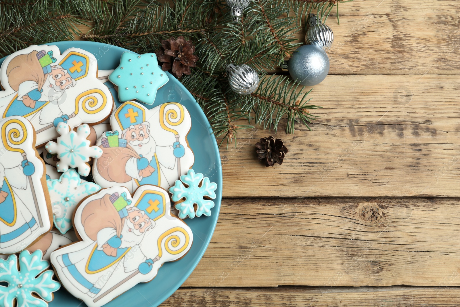 Photo of Tasty gingerbread cookies and festive decor on wooden table, flat lay with space for text. St. Nicholas Day celebration