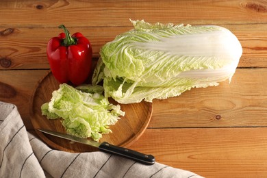 Photo of Fresh Chinese cabbage, pepper and knife on wooden table, above view