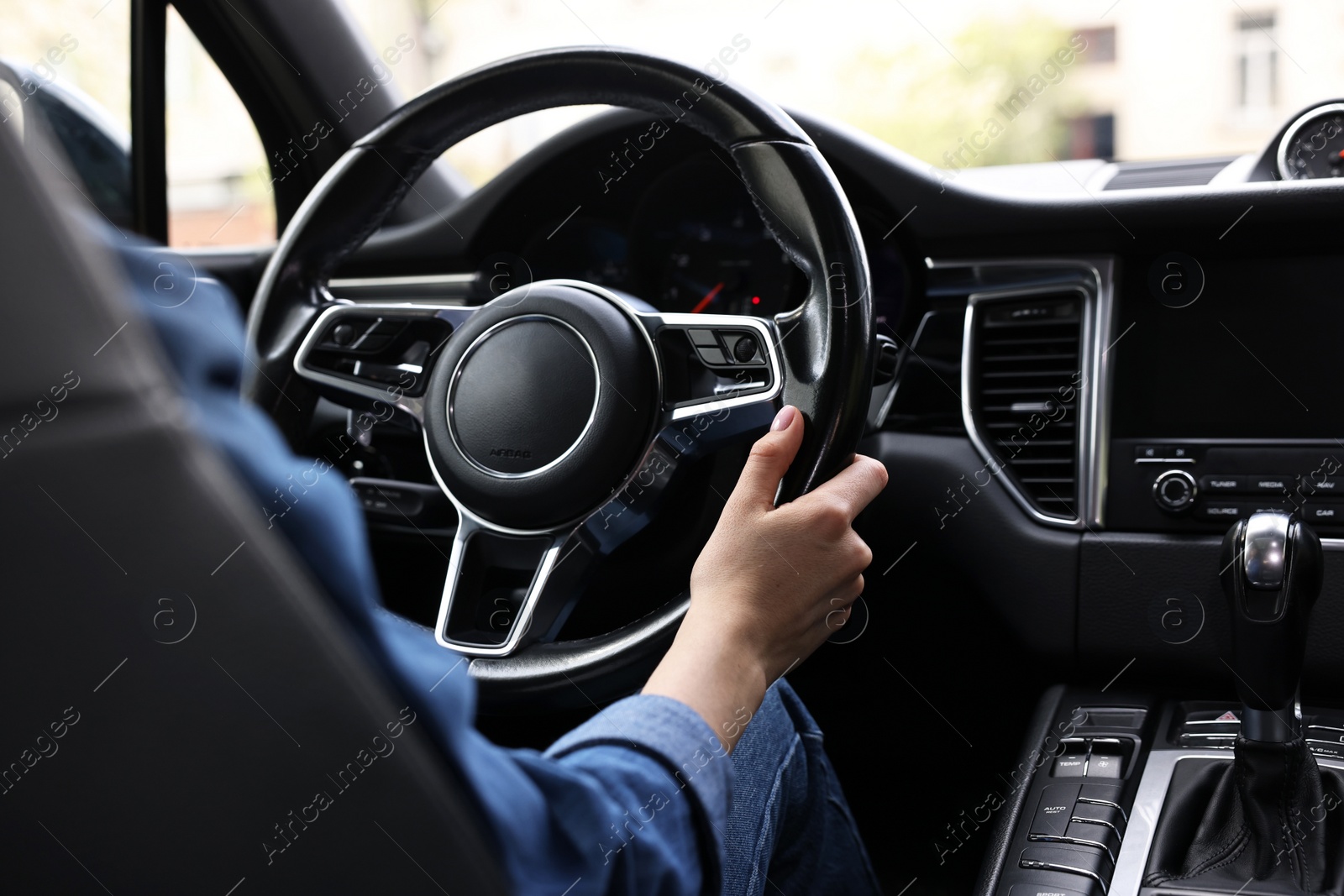 Photo of Woman holding steering wheel while driving her car, closeup