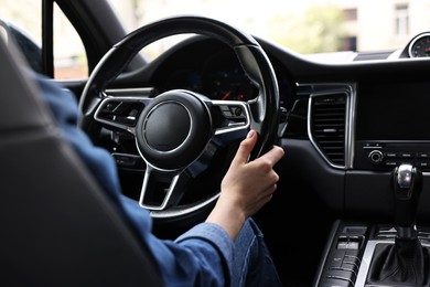 Woman holding steering wheel while driving her car, closeup