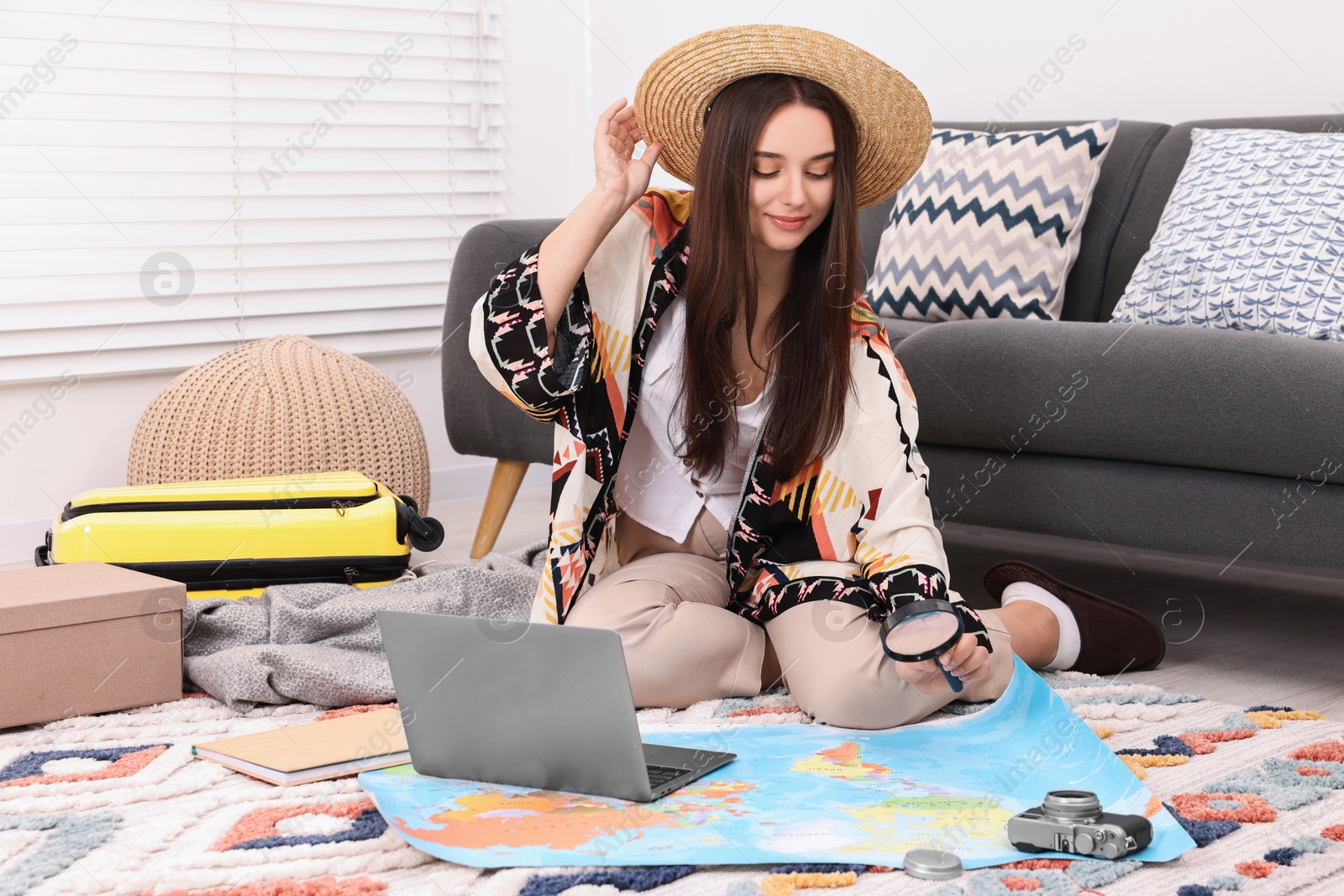 Photo of Travel blogger with magnifying glass and map planning trip at home