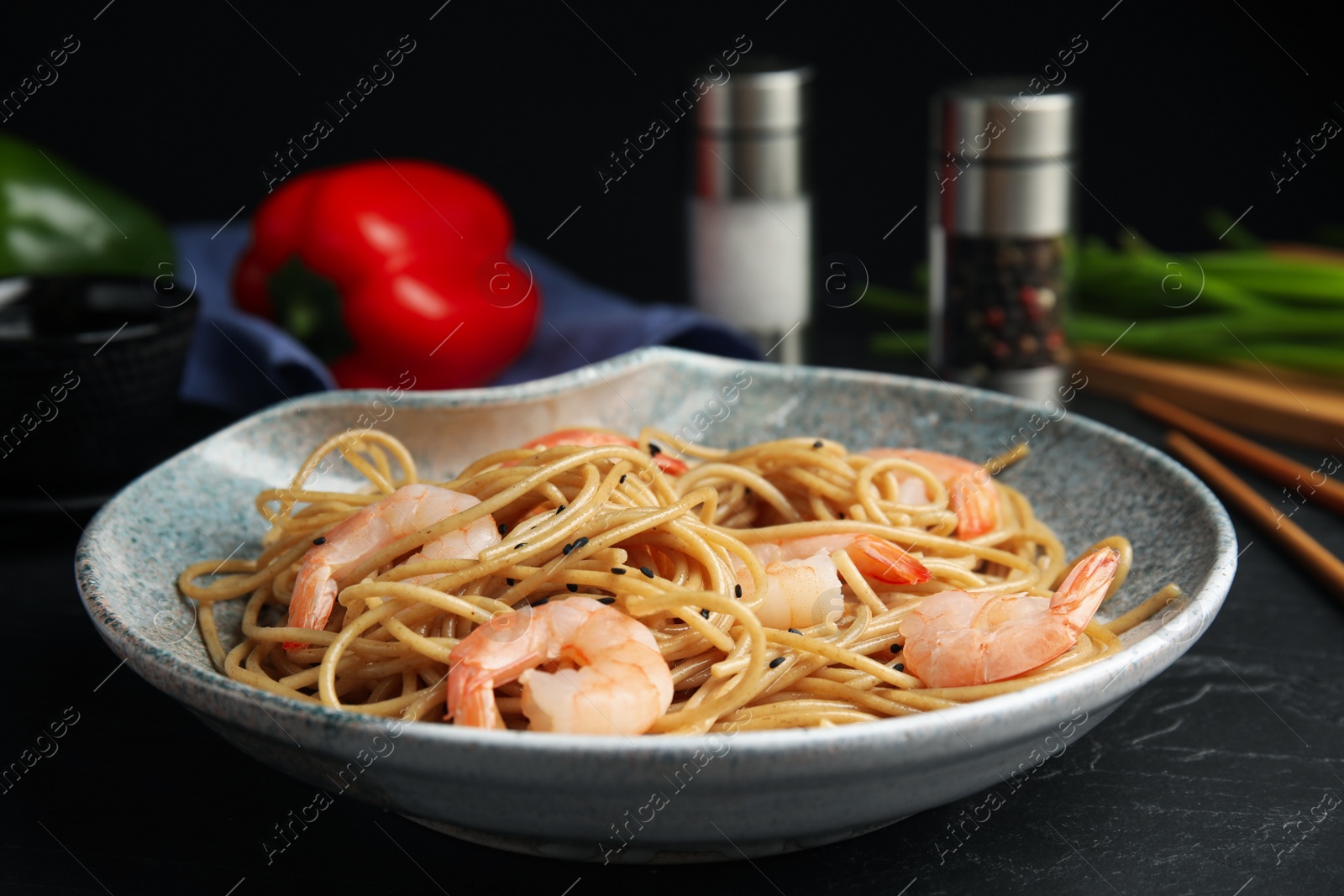 Photo of Tasty buckwheat noodles with shrimps served on black table