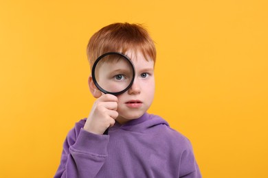 Photo of Boy looking through magnifier glass on yellow background