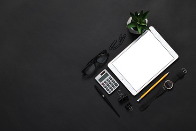 Photo of Modern tablet, stationery, glasses and wristwatch on black background, flat lay. Space for text