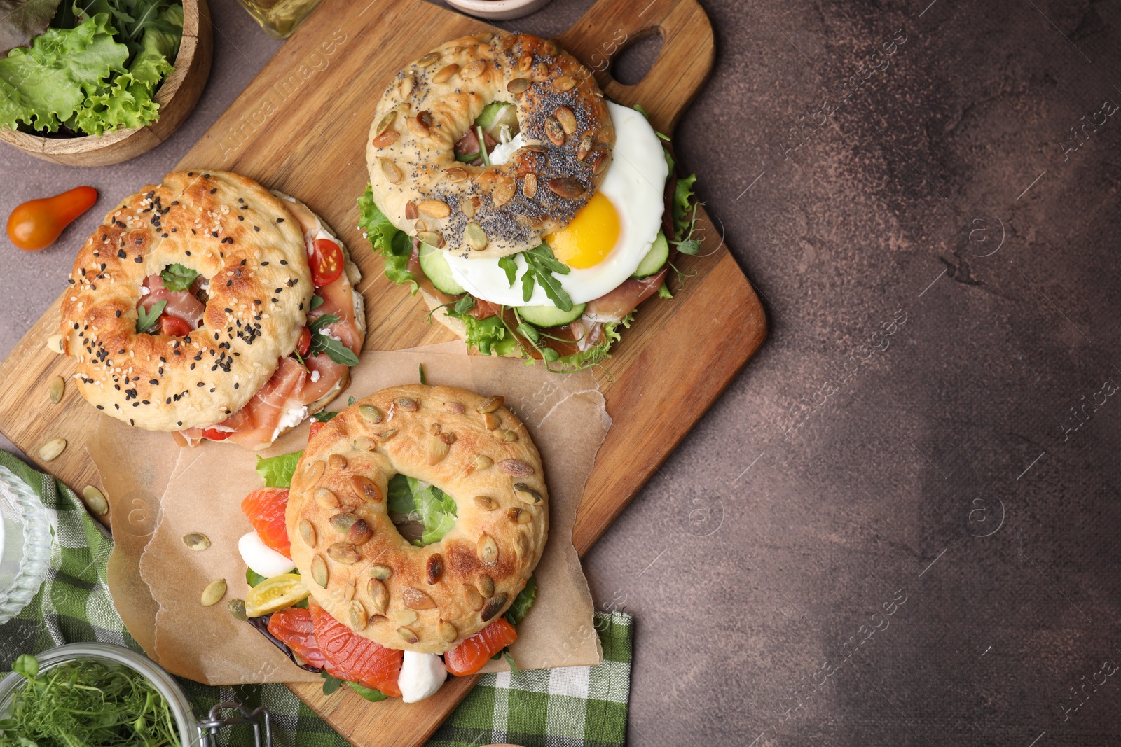 Photo of Tasty bagel sandwiches on brown table, flat lay. Space for text