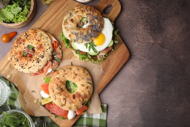 Tasty bagel sandwiches on brown table, flat lay. Space for text