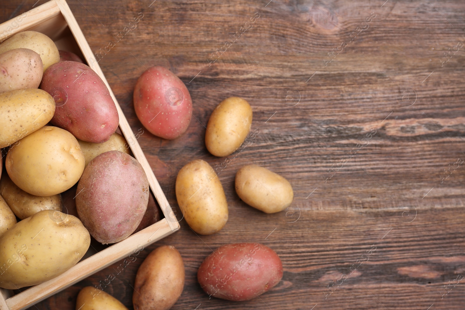 Photo of Fresh organic potatoes on wooden background, top view