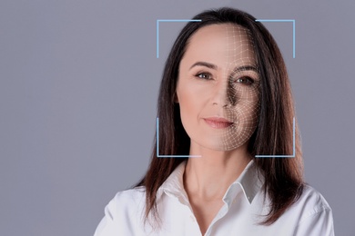 Image of Facial recognition system. Woman with scanner frame and digital biometric grid on grey background, space for text