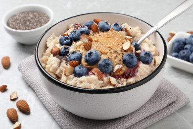 Photo of Tasty oatmeal porridge with toppings served on light grey table