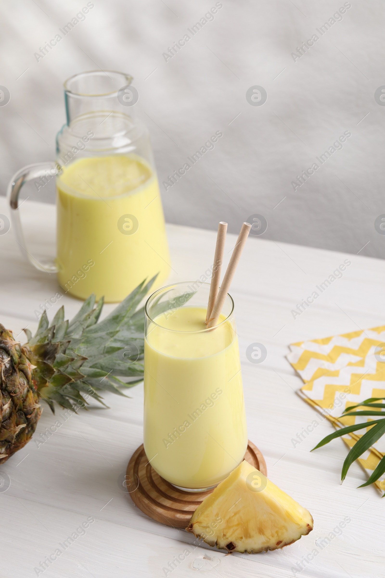 Photo of Tasty pineapple smoothie on white wooden table