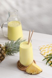 Tasty pineapple smoothie on white wooden table