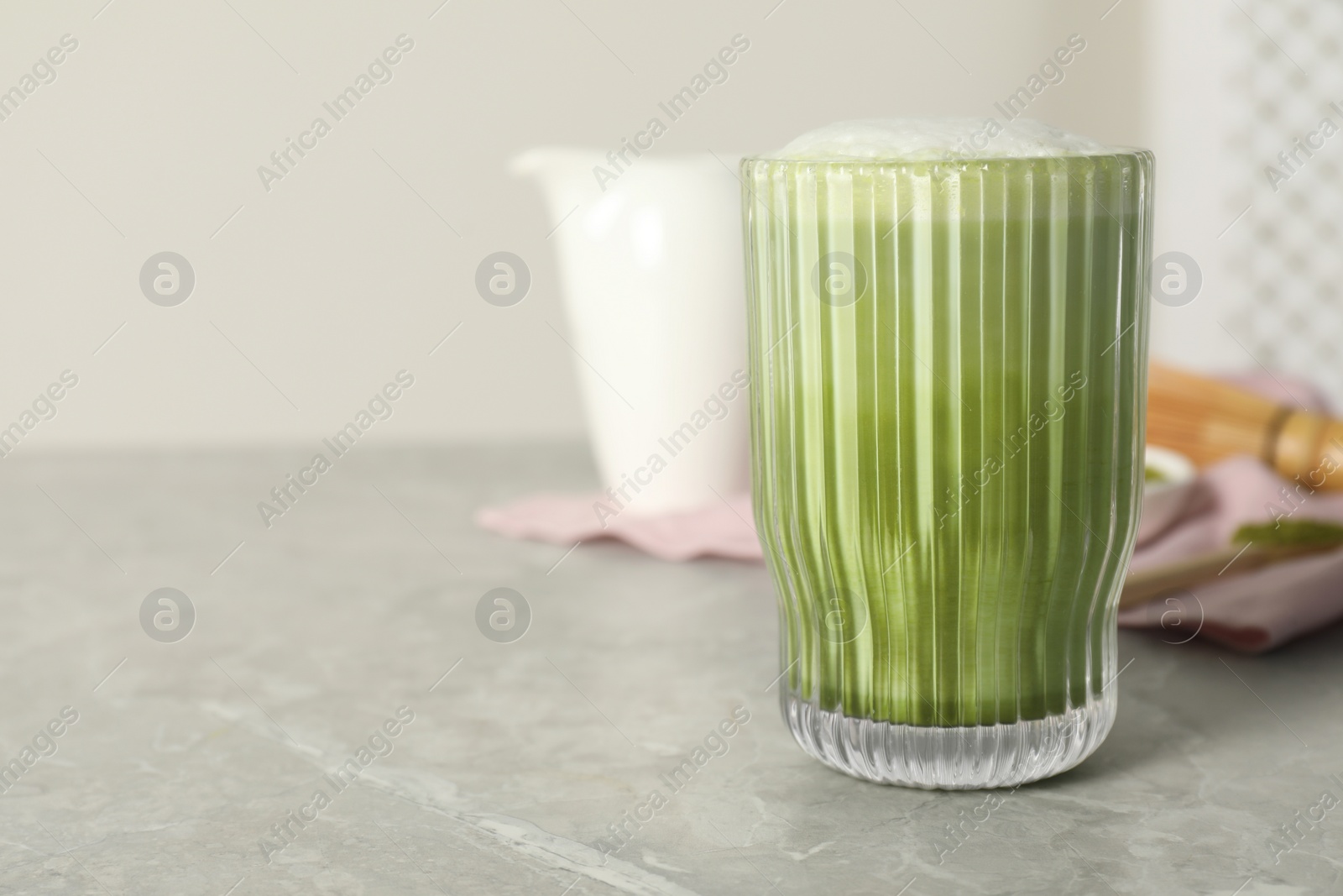 Photo of Glass of tasty matcha latte on light gray marble table, space for text