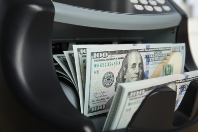 Photo of Modern electronic bill counter with money, closeup