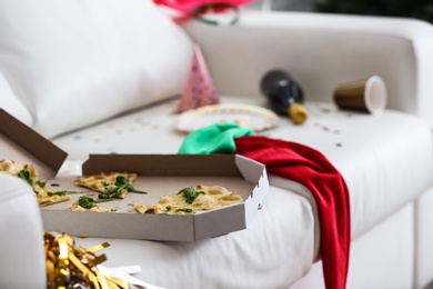 Photo of Pizza box with leftovers on messy sofa. Chaos after party