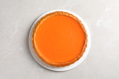 Photo of Fresh delicious homemade pumpkin pie on light background, top view