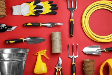 Flat lay composition with gardening tools on red background