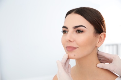 Photo of Dermatologist examining young patient's birthmark in clinic. Space for text