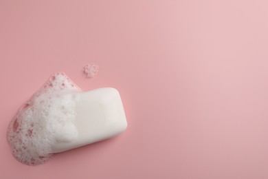 Photo of Soap with fluffy foam on pink background, top view. Space for text