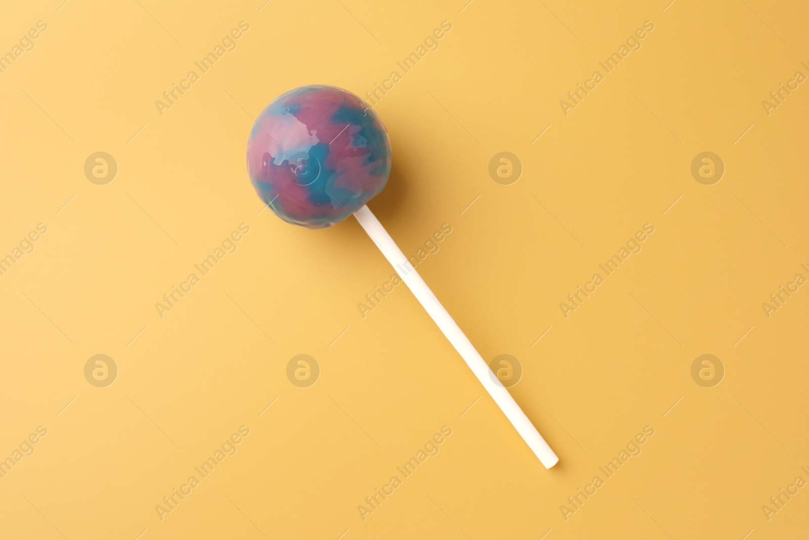 Photo of Tasty lollipop on yellow background, top view