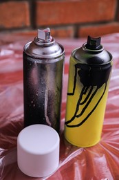 Photo of Used cans of spray paints on table. Graffiti supplies