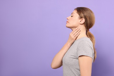 Woman suffering from sore throat on violet background. Space for text