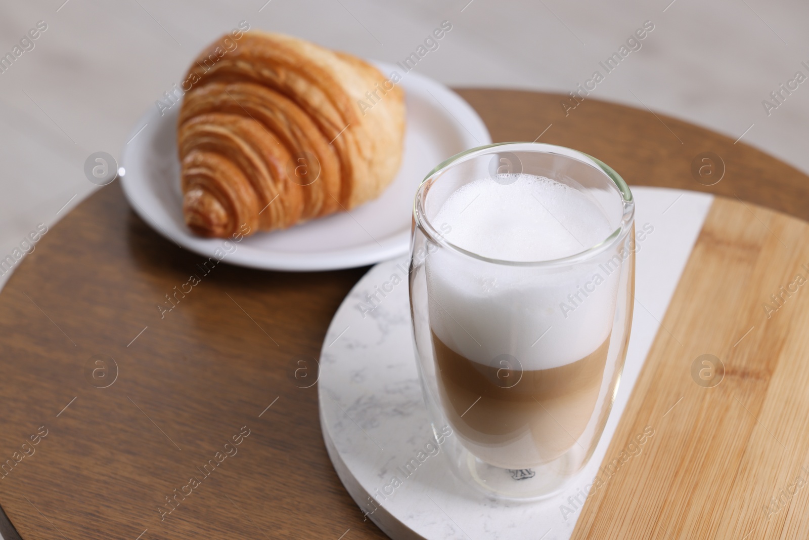 Photo of Aromatic latte macchiato in glass and croissant on wooden table