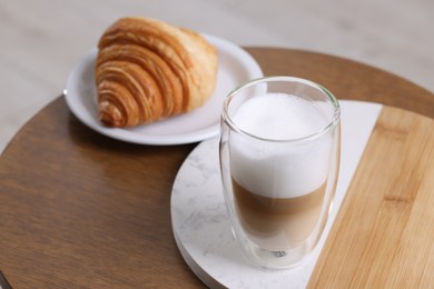Photo of Aromatic latte macchiato in glass and croissant on wooden table