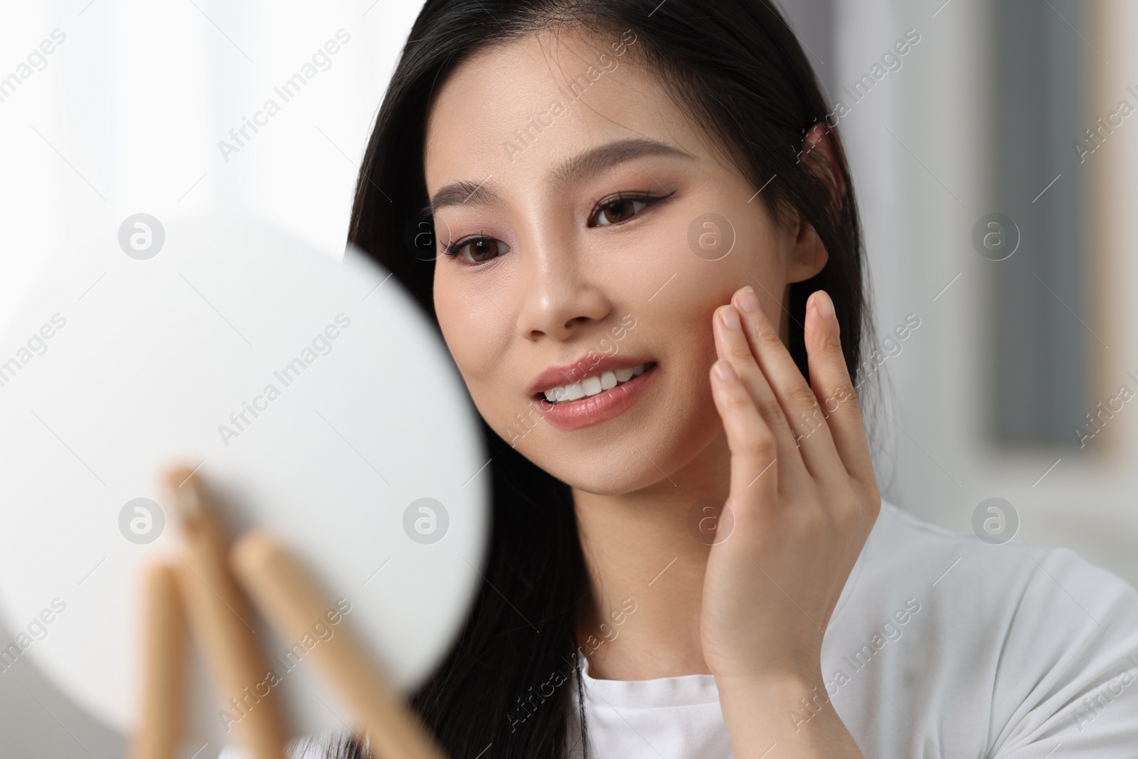 Photo of Woman with perfect skin looking at mirror indoors