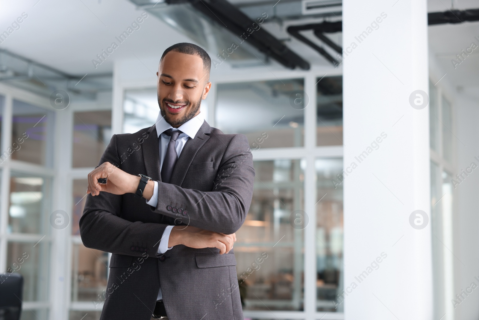 Photo of Happy man looking at his watch in office, space for text. Lawyer, businessman, accountant or manager