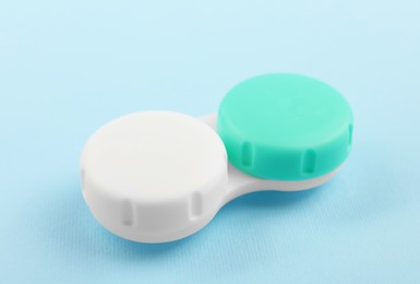 Case with color contact lenses on light blue background