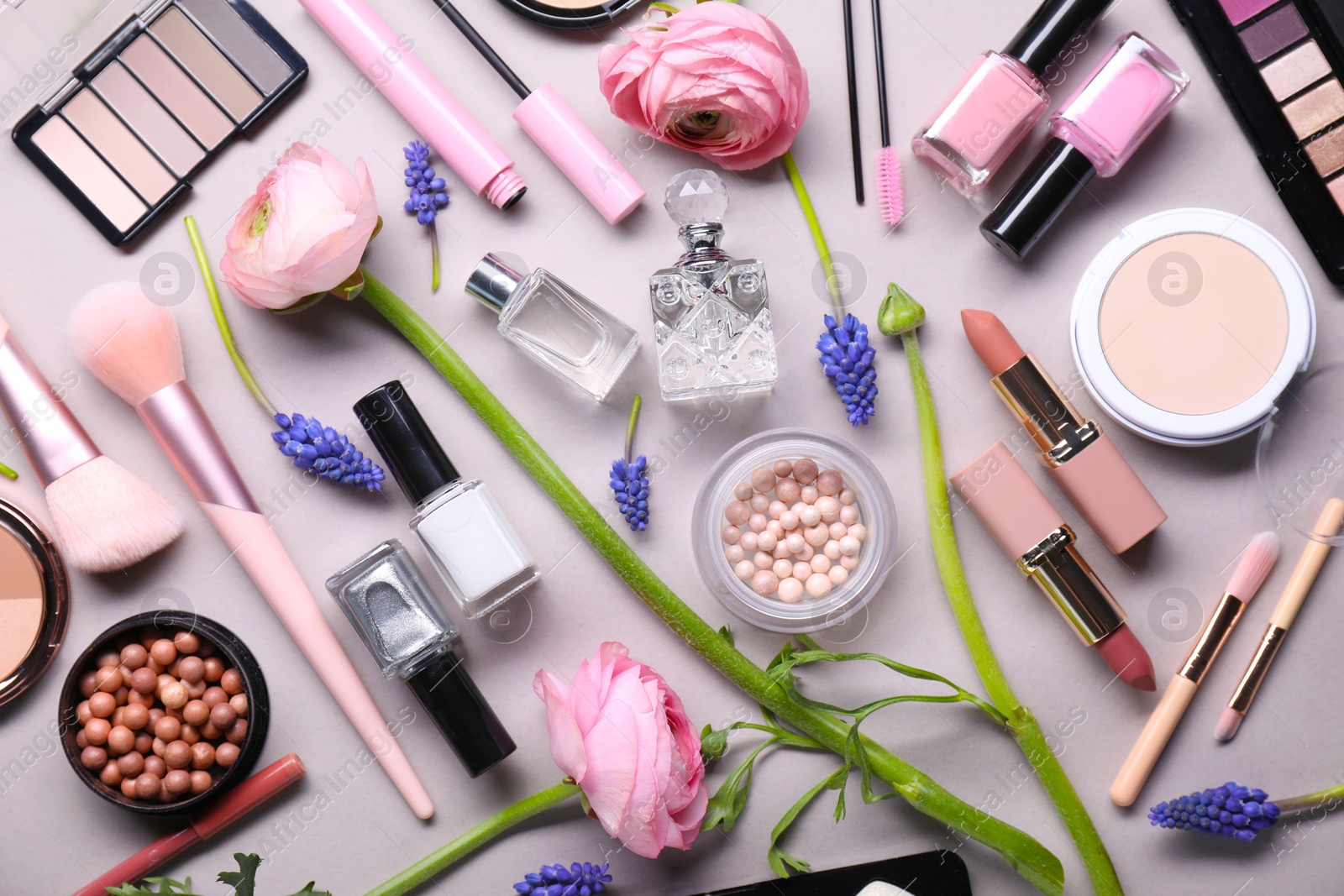 Photo of Flat lay composition with different makeup products and beautiful spring flowers on gray background